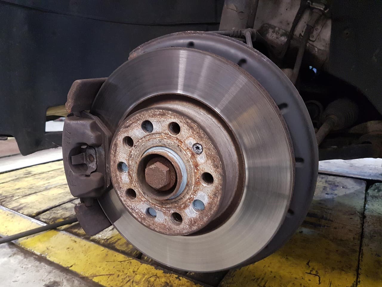 A brake disc and caliper on a car raised in the workshop