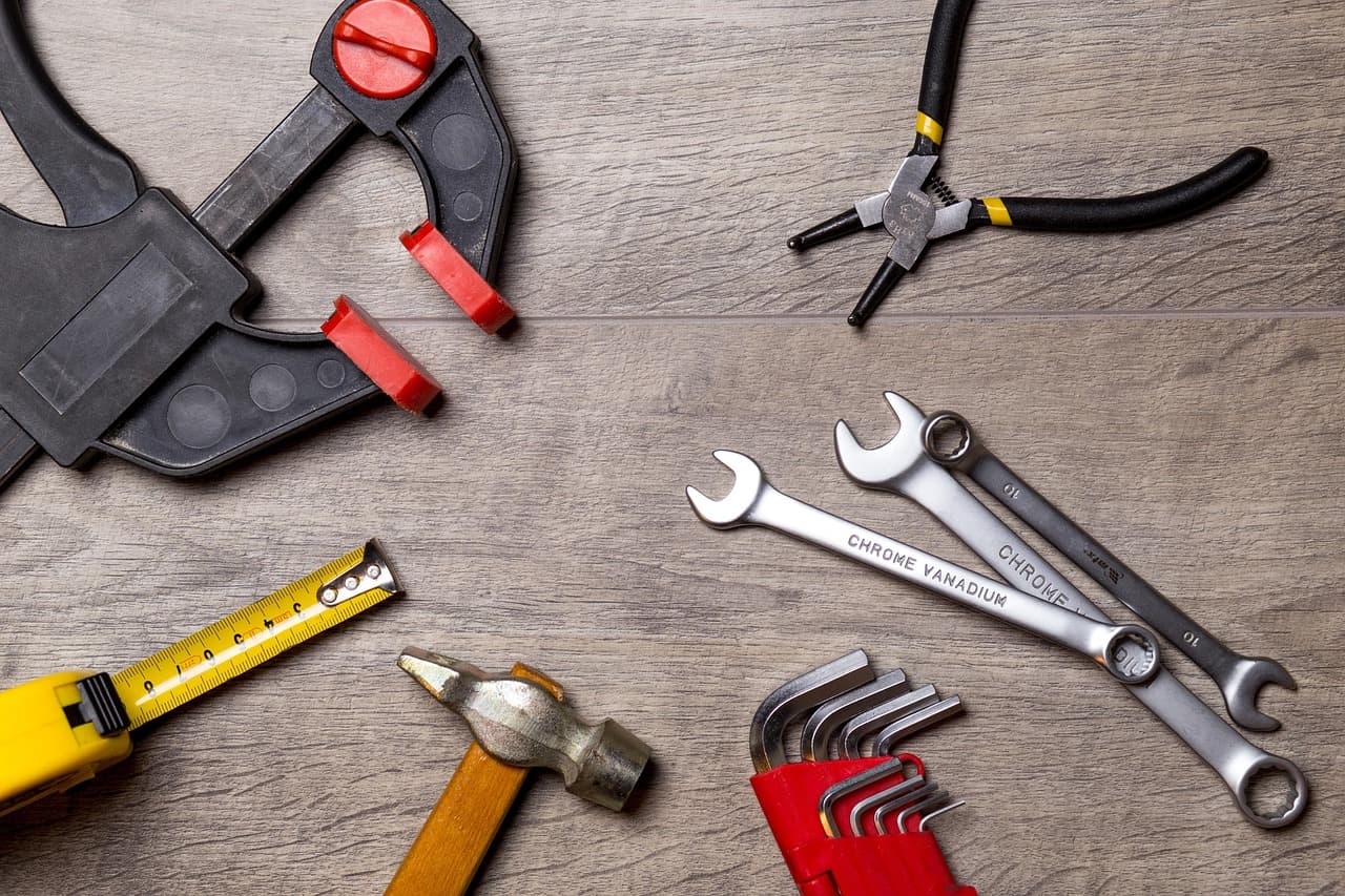 Spanners, pliers, a hammer and a tape measure laid out on a workbench